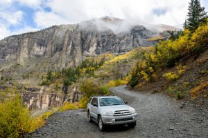 Telluride, Colorado, USA - October 05, 2015: on a cloudy and foggy autumn day, a four-wheel-drive SUV is exploring in colorful autumn mountains on the winding Black Bear Pass trail, near Telluride, Colorado, USA.